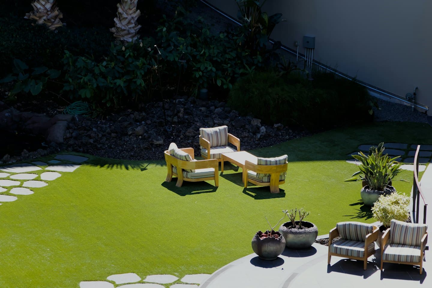 Moderne Terrassenmöbel stehen auf Kunstrasen und Steinwegen.